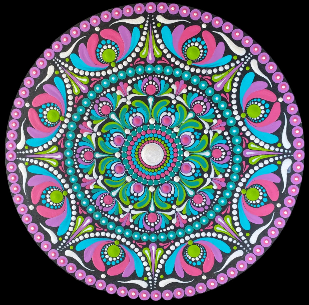 A circular mandala art piece with a vibrant multicolor design featuring pink, teal, green, and white patterns, displayed on a black background.